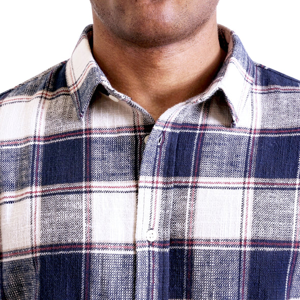 close up view of the collar and neck area of woven button up shirt showing off the pointed collar and deep blue plaid flannel fabric on a black male model