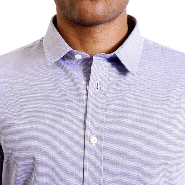 close up view of the pointed collar and neck area of soft blue cotton fabric button up shirt showing the small diamond texture woven into the shirt. Worn by a black male model. The top buttons are undone