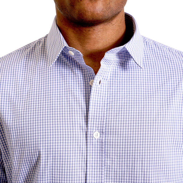 close up view of the pointed collar and neck area of cotton fabric button up shirt in a blue and white gingham pattern. Worn by a black male model. The top buttons are undone