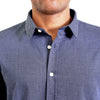 Close up view of the pointed collar and neck area of navy blue organic cotton fabric button up shirt. Worn by a black male model. The top buttons are undone