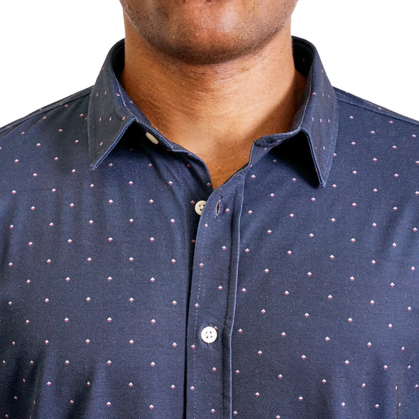 close up view of the pointed collar and neck area of knit fabric button up shirt in navy ground with small dot geometric pattern on a black male model. The top buttons are undone