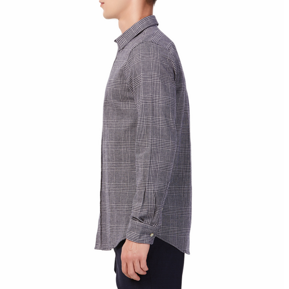Men's black and white plaid patterned,  long sleeve button up shirt with a pointed collar on a model. Image is cropped to the torso and model is facing to the side so the arm is facing the viewer
